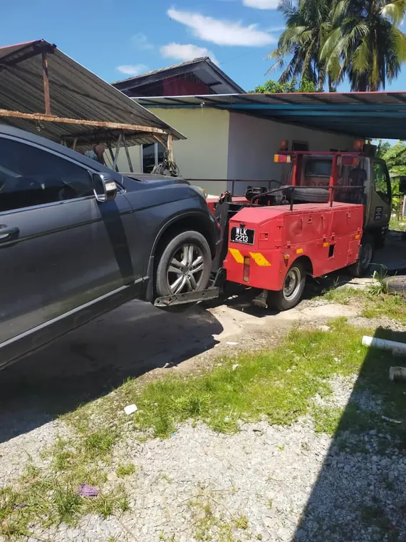 Lori tunda merah kami menunda SUV waktu siang di Kelantan